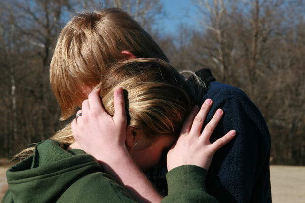 Teen boy and girl in comforting embrace