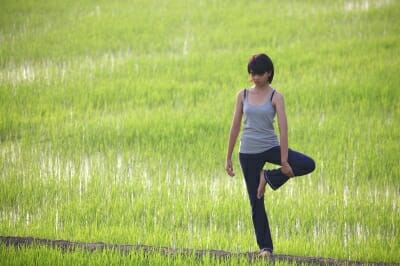 Woman in Yoga pose in a green field