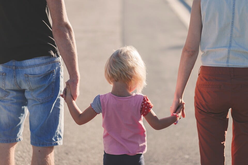 Parents and young daughter walking hand in hand