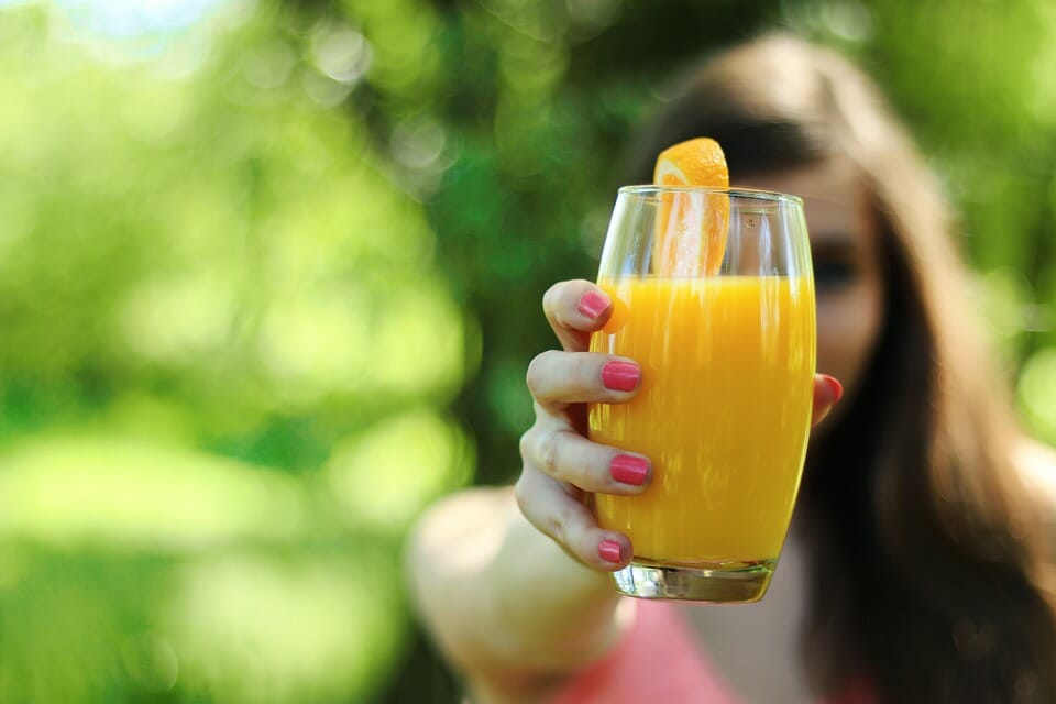 Girl holding out orange juice