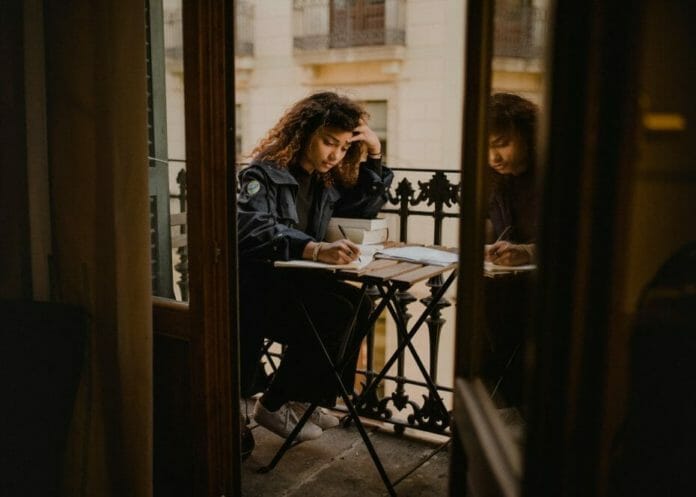 Student on a balcony with books and notes