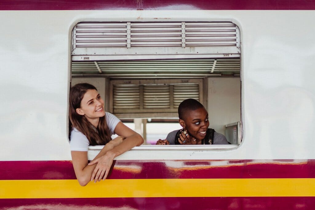 Young women smiling on a self-care getaway train